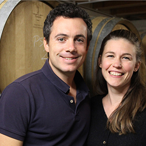 Two people in front of wine barrels. Domaine de la Monette