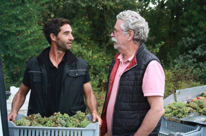 A man holding a tote of grapes, looking at another man, Domaine de la Taille aux Loups