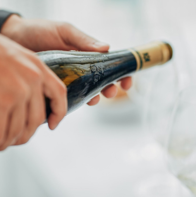 close up of hands holding a bottle of wine horizontally