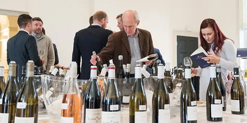 People writing about the bottles of wine that stand on the table in front of them