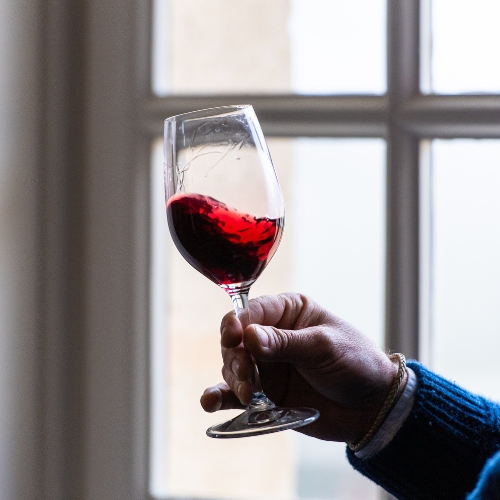 man's hand holding a swishing glass of red wine