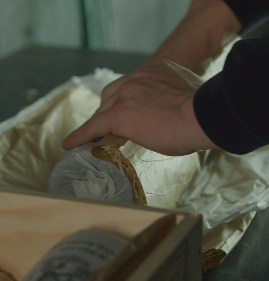 A Person wrapping a bottle of wine for storage