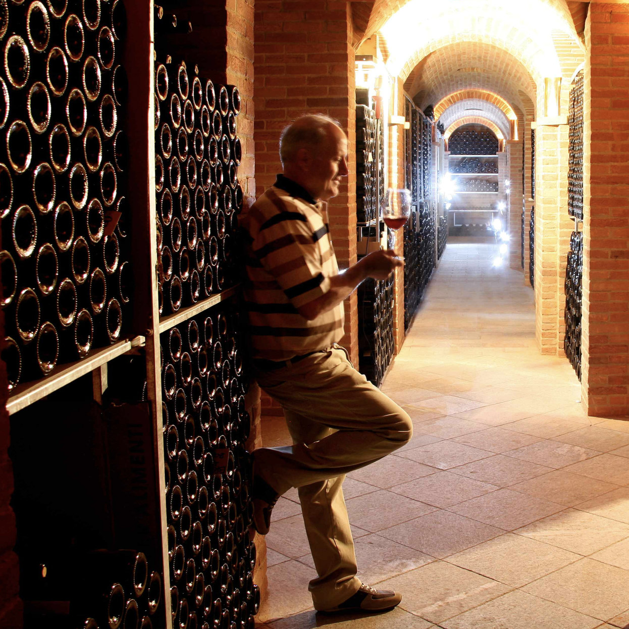 man standing against a case of wine bottles