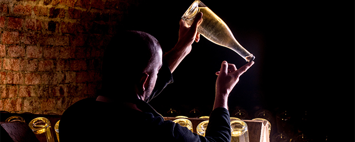 Philipponnat Clos des Goisses worker holding a bottle of champagne in a dark cellar