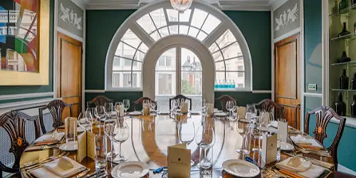 A long dining table, set for eating, in front of an arch window