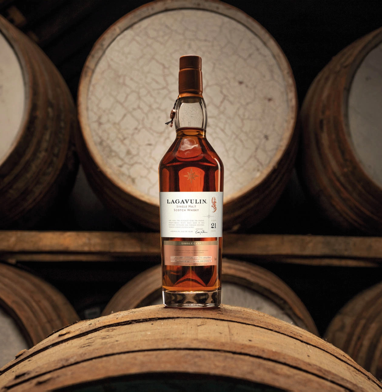 whisky bottle in front of wooden casks