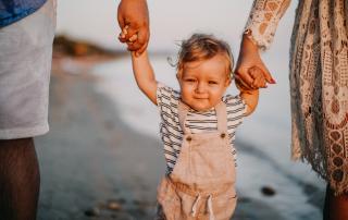 Parents and toddler walking along the beach holding hands
