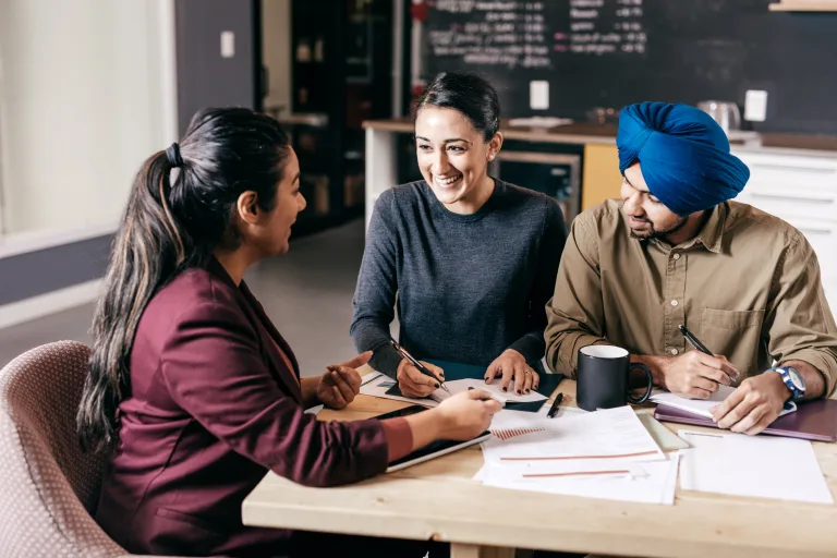 A couple talking with an advisor, seated at table looking attentive