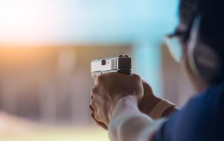 Person holding a firearm taking aim