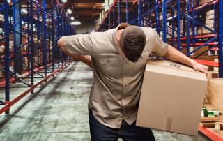 Man holding box in warehouse, holding his back
