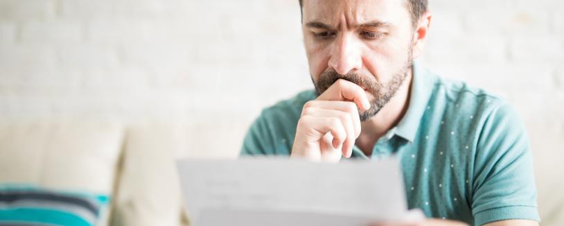 Bearded man looking pensive, looking at piece of paper