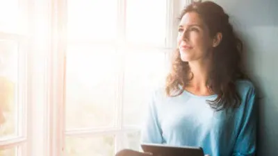 A women holding a tablet looking out a window