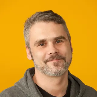 Headshot of man wearing grey sweatshirt. 