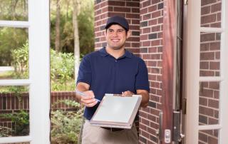 Man at door, holding clipboard to be signed