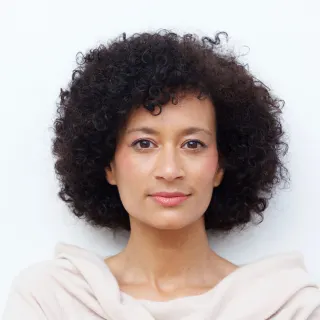 Headshot of woman with short curly hair wearing white shirt. 