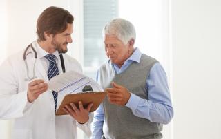 A doctor shows a clipboard to an older man