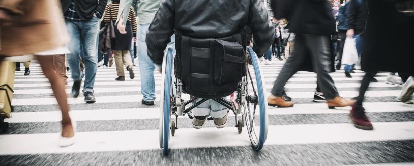 Person in wheelchair crosses busy crosswalk