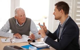 An older man consulting with an advisor, sitting at table