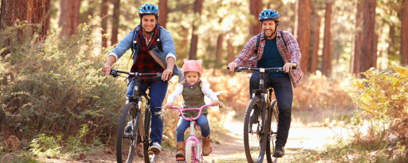 Couple with daughter cycling along forest path
