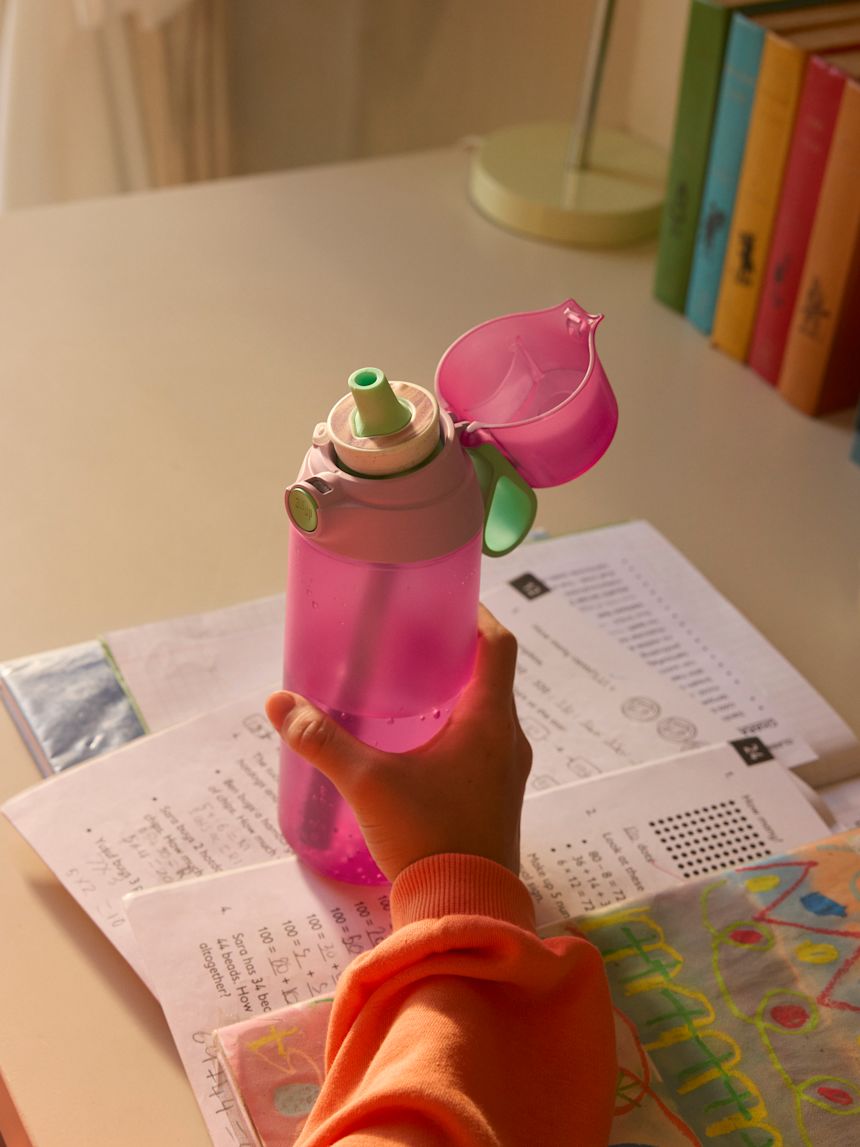 A child holds the air up bottle over homework at a desk