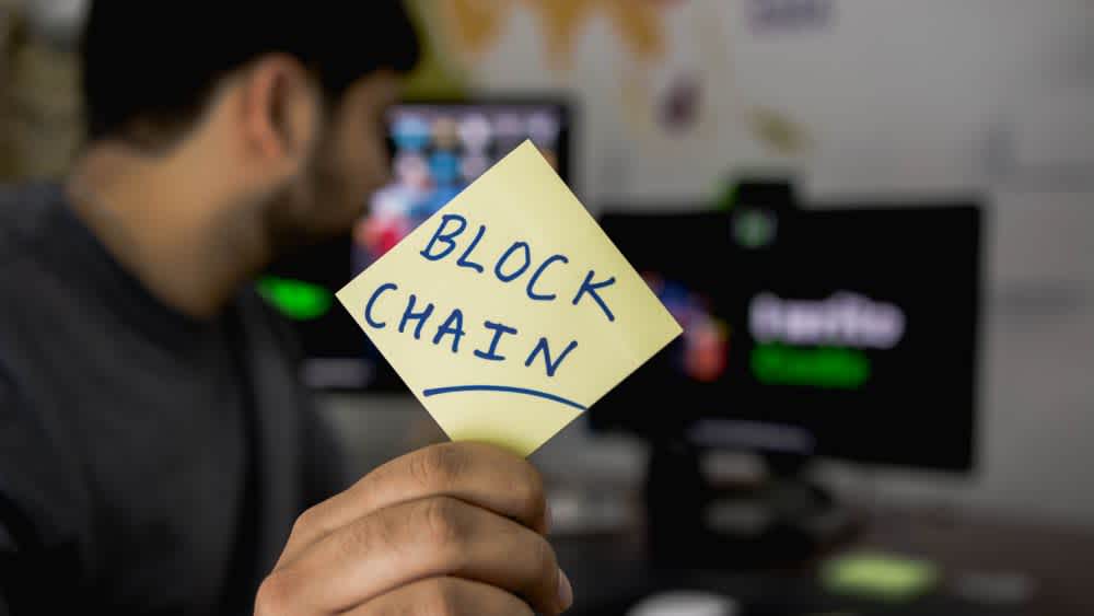 Man holding post-it note with "block chain" written