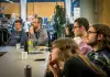 A group of individuals gathered around a table in a well-lit room, engaged in a discussion or meeting.