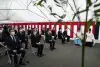 Executives and priests sitting down during ceremony.