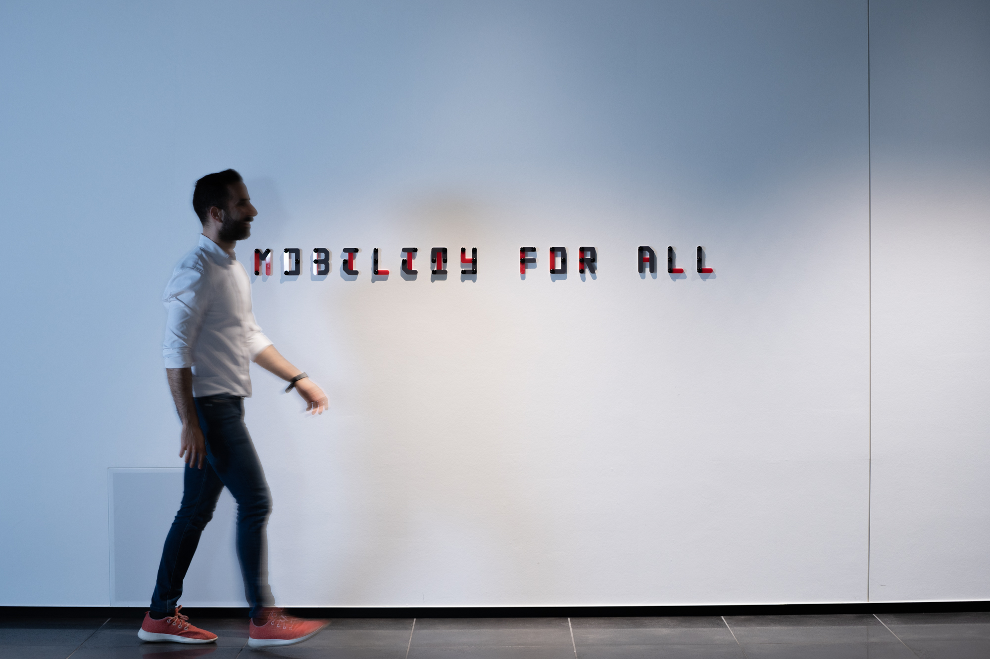 Man walking past "Mobility for All" sign at the Woven by Toyota office