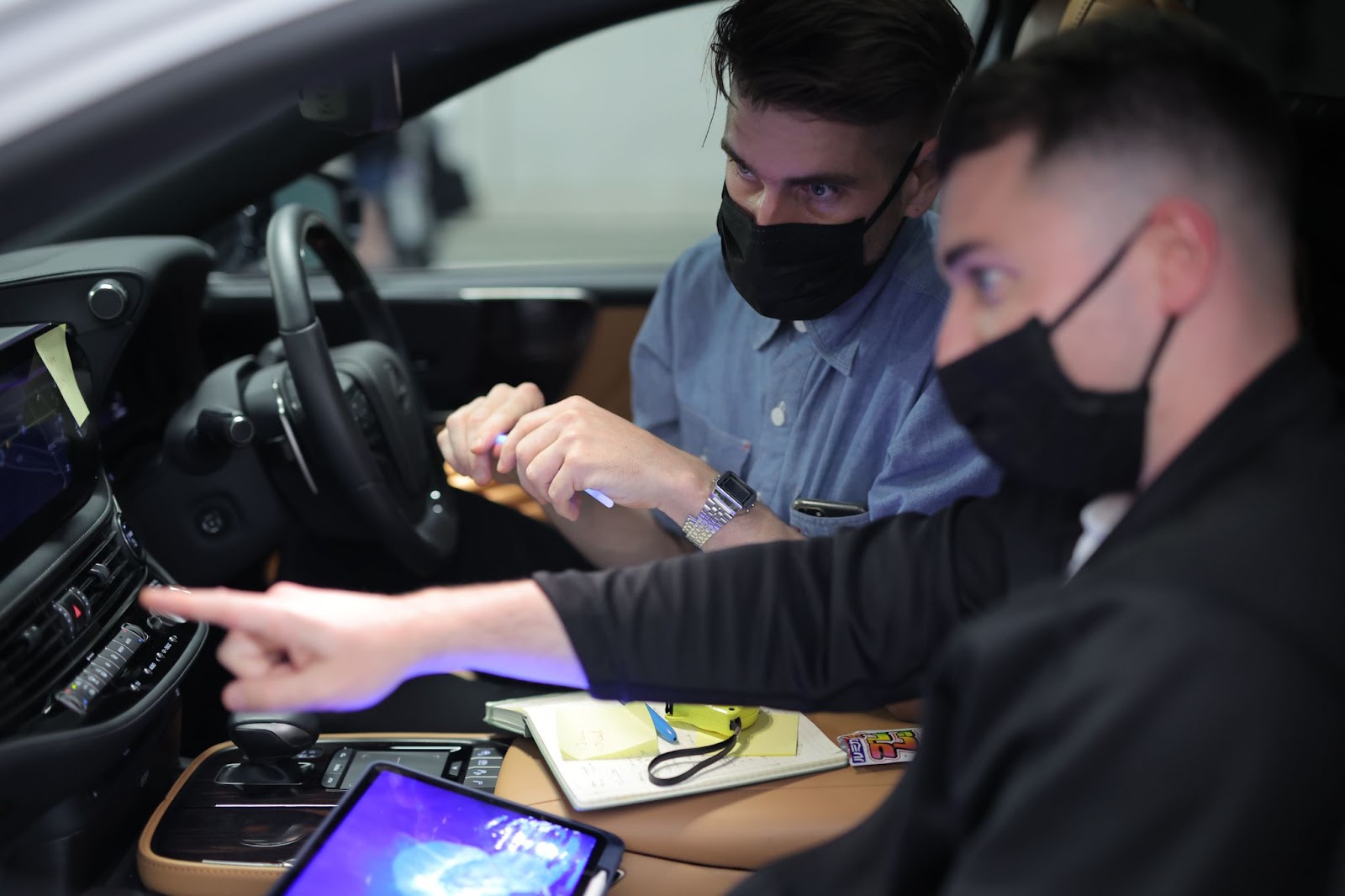 Two men checking the infotainment screen inside a car