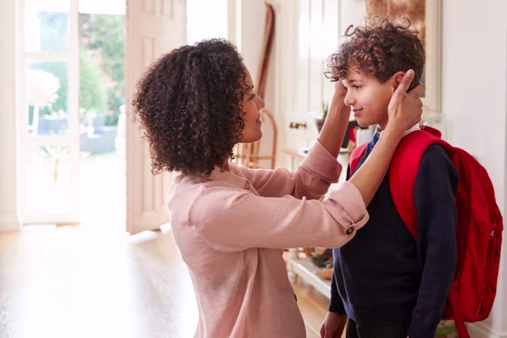 Mother showing son attention who is in a school uniform and backpack