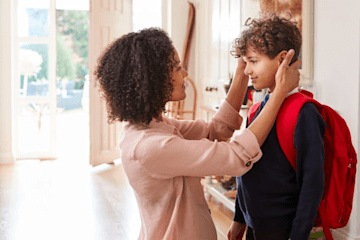 Mother showing son attention who is in a school uniform and backpack