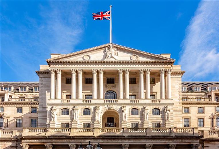 The Bank of England, a white, marble building with columns, against a bright blue sky