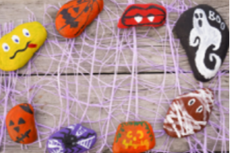 A circle of painted rocks. The designs includes ones of scary pumpkins, spiders and ghosts.