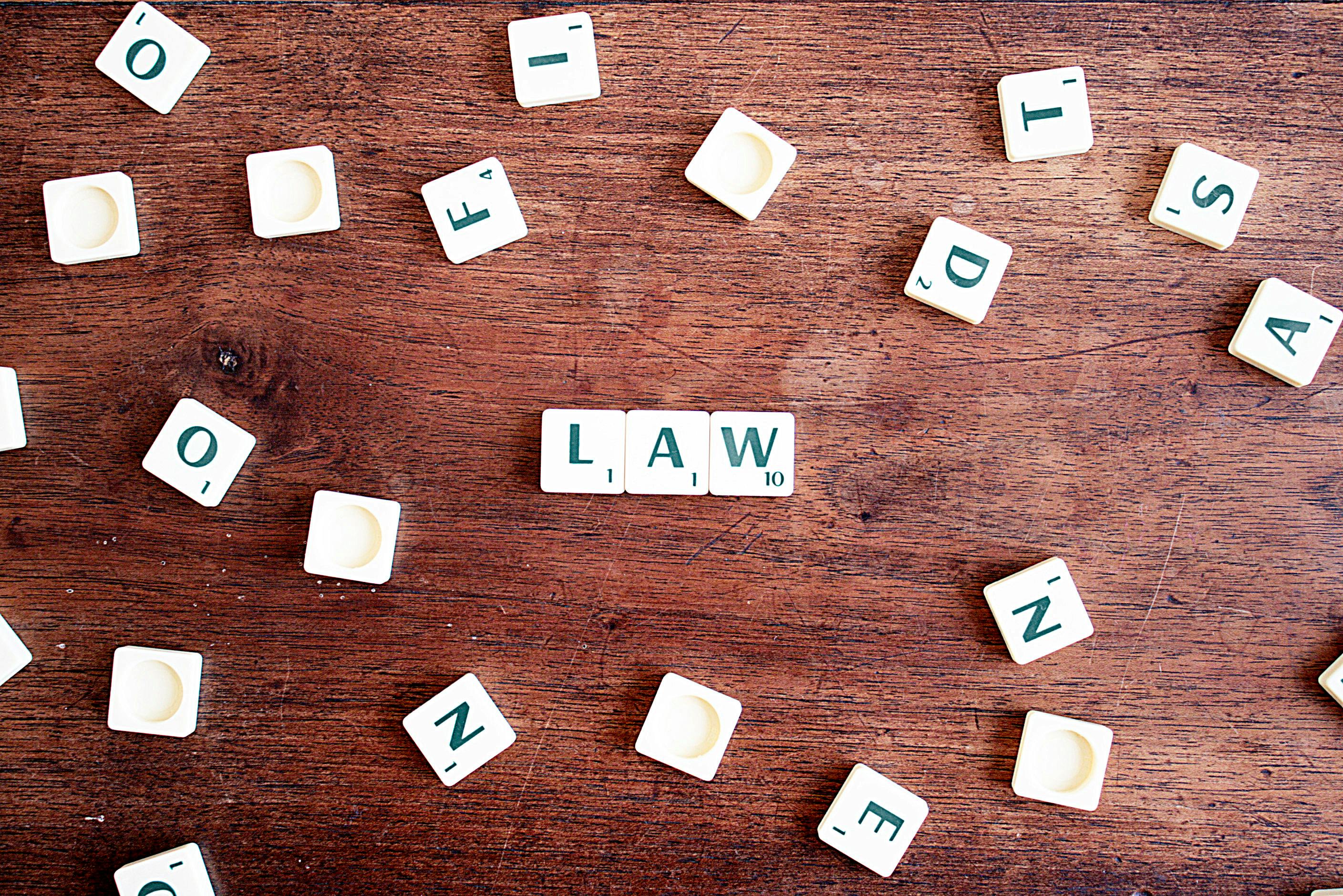 A random scatter of Scrabble letter tiles, with three in the centre spelling "law".