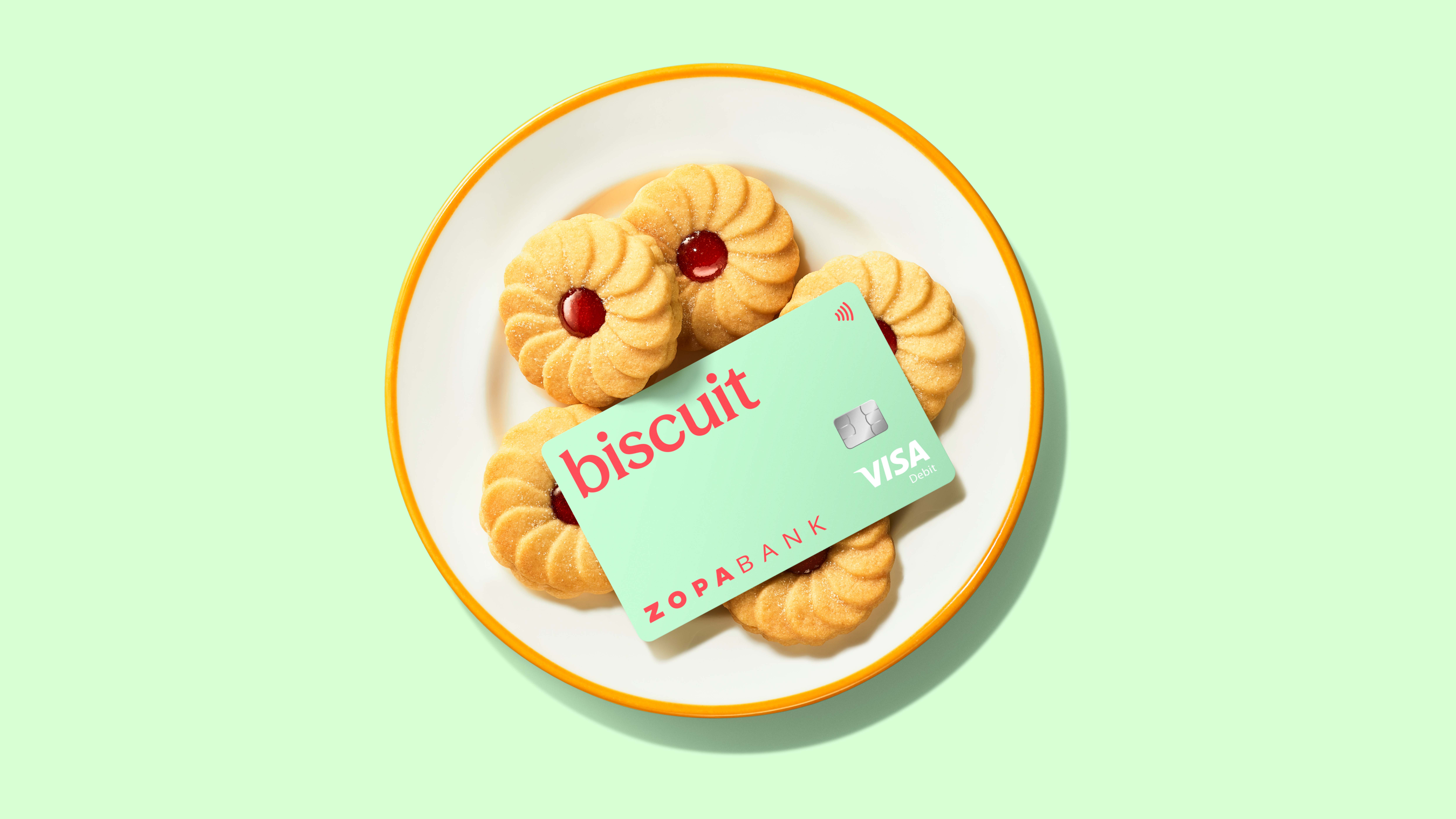 Mint green Zopa Biscuit debit card sitting on plate of Jammie Dodgers