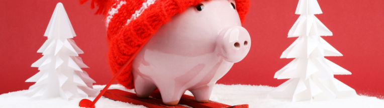Image shows a piggy bank on skis with a wooly hat - the skis and hat are red. The background is red and there are two pine trees made out of paper