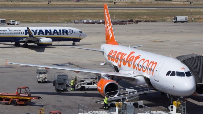 Photo of a Ryanair plane and an Easyjet plane on the runway at an airport.