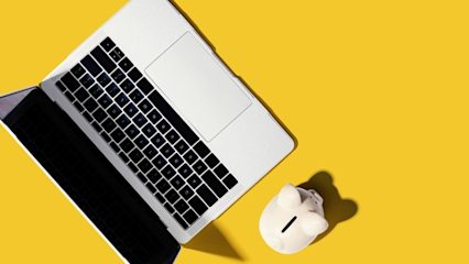 Laptop with a piggy bank next to it on a yellow background