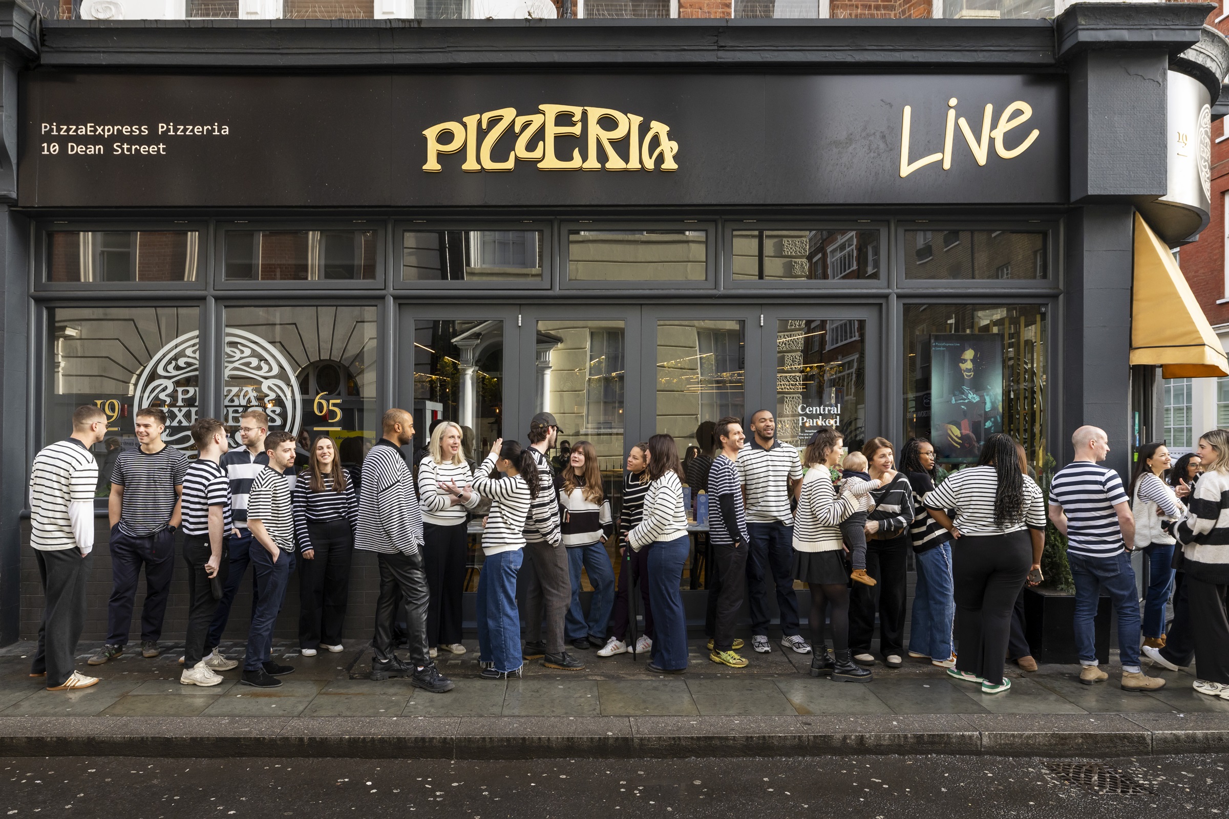 Image showing people wearing black and white striped tops queuing outside a Pizza Express restaurant