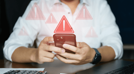 A person wearing a white button-down shirt, holding a phone with red caution sign illustrations coming off of it