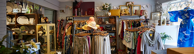 Image shows a charity shop with a range of clothes that look vintage