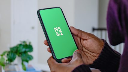 A person holding a phone with the NS&I logo showing on the screen.