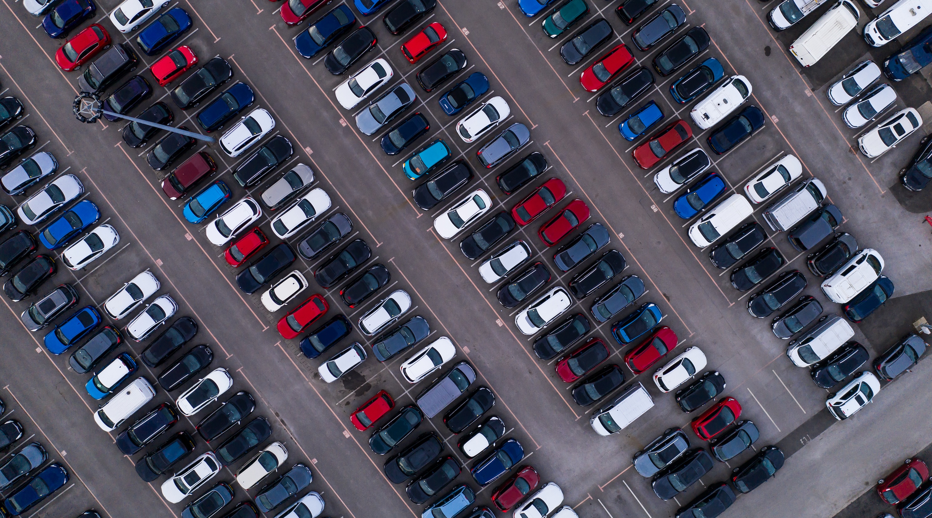 Image shows an aerial view of a car park filled with cars