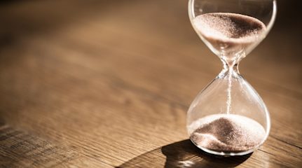 Hourglass filled with golden sand on a wooden table