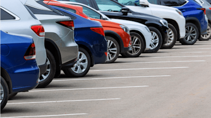A line of silver, red, blue and black parked cars.