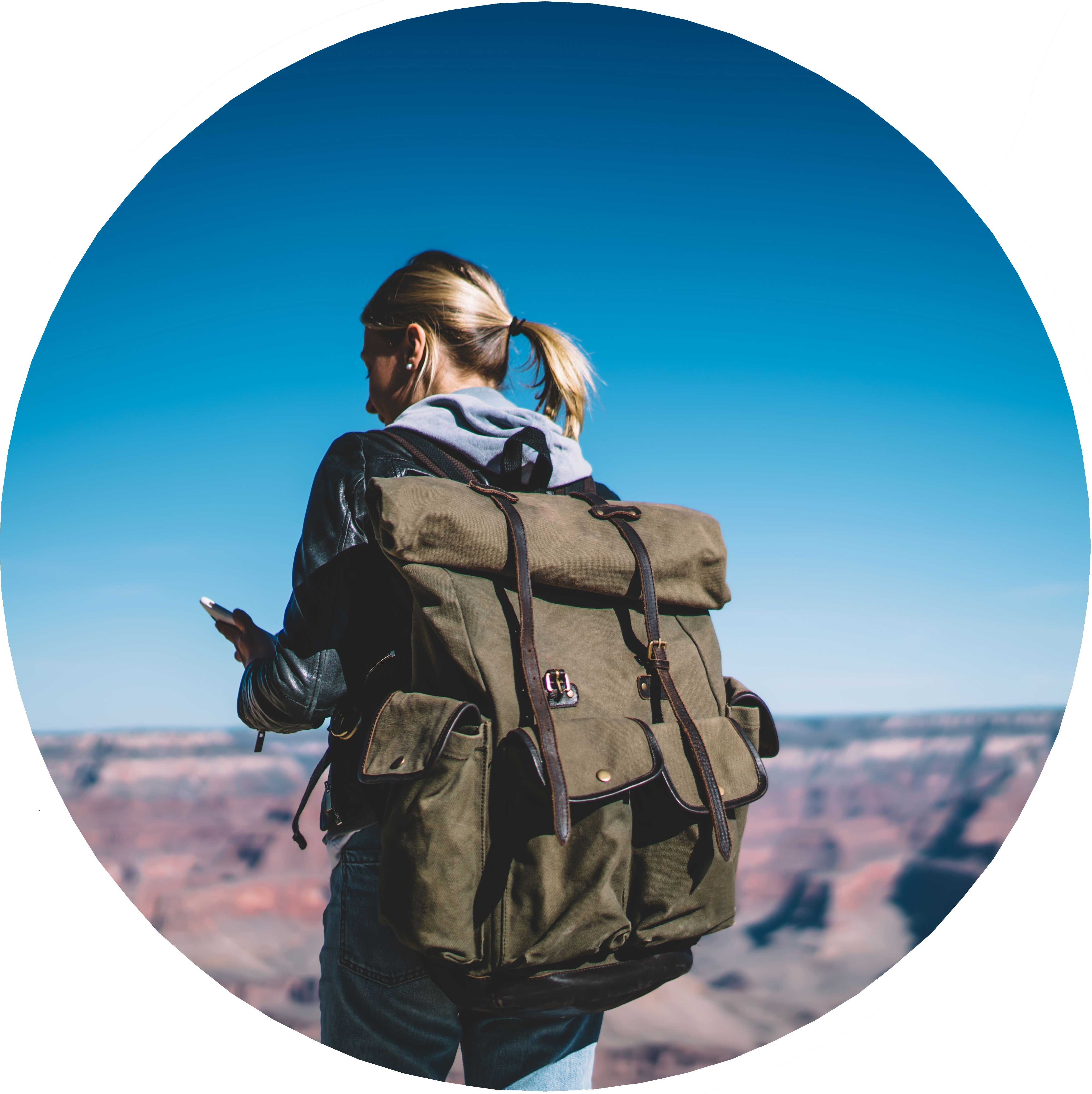 A woman is looking at her phone in front of a mountainous backdrop.