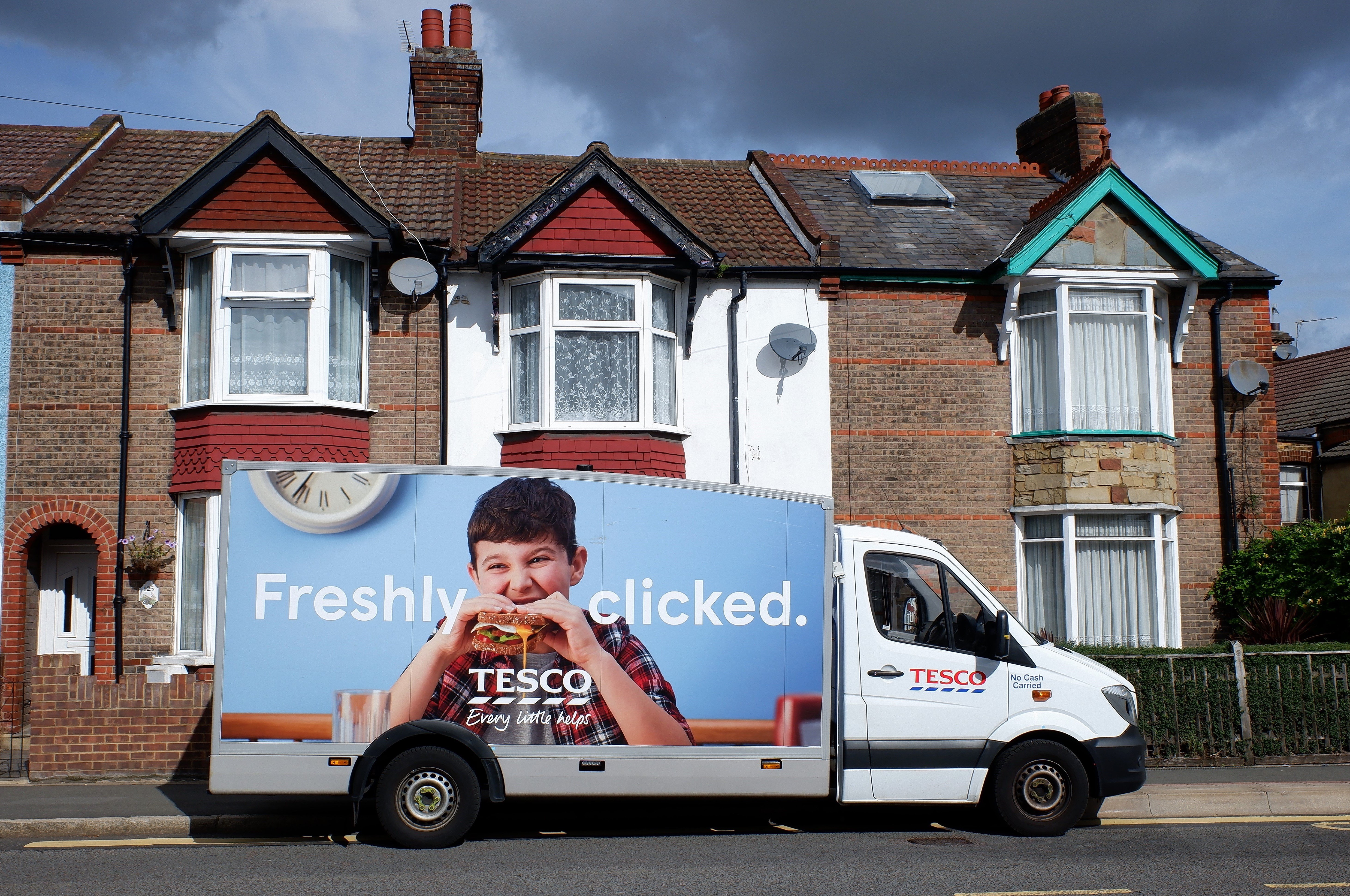 Tesco delivery van parked outside row of terraced houses