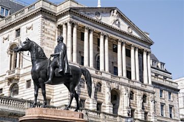 A metal statue of a man riding a horse in front of the Bank of England