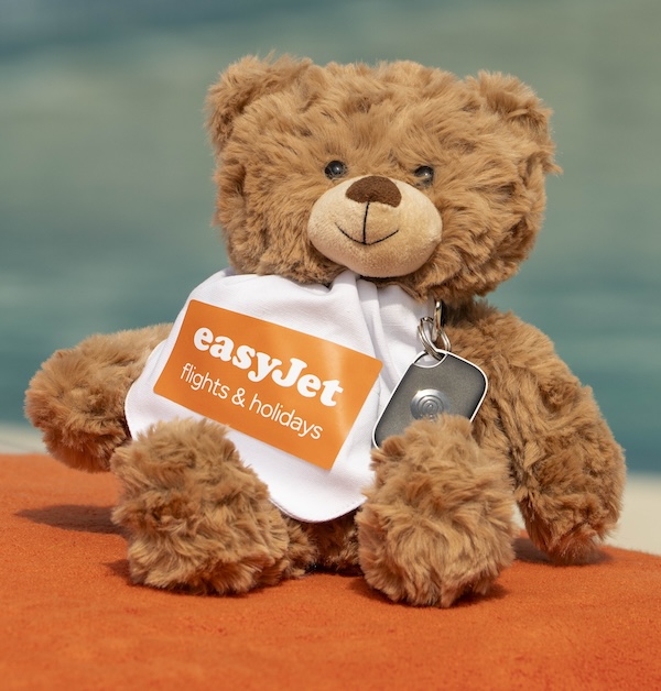 A teddy bear with an Easyjet vest on and a small, black tracking device clipped to him
