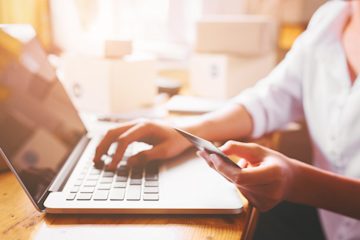 A person holding a credit card and looking at a laptop computer